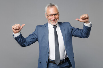 Smiling elderly gray-haired mustache bearded business man in classic blue suit shirt tie isolated on grey background studio. Achievement career wealth business concept. Pointing thumbs on himself.