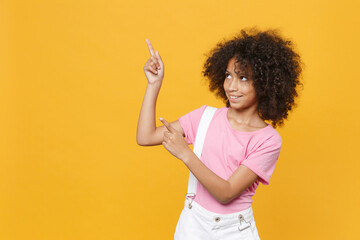 Smiling little african american kid girl 12-13 years old in pink t-shirt isolated on yellow wall...