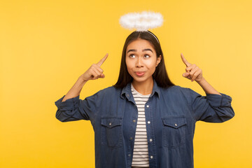 Look, I'm saint! Portrait of innocent girl pointing at nimbus over head, showing to be obedient...