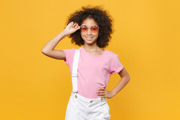 Smiling little african american kid girl 12-13 years old in pink t-shirt eyeglasses isolated on...