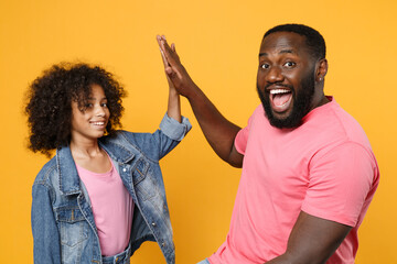 Excited african american guy girl brother sister in denim pink clothes posing isolated on yellow...