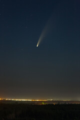 Comet C / 2020 F3 (NEOWISE) in the night starry sky over the city with street lighting. Bright...