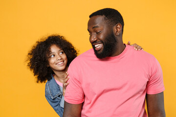 Smiling african american guy girl brother sister in denim pink clothes isolated on yellow wall background studio portrait. People lifestyle concept. Mock up copy space. Hugging, looking at each other. - Powered by Adobe
