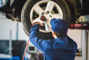 Mechanician changing car wheel in auto repair shop