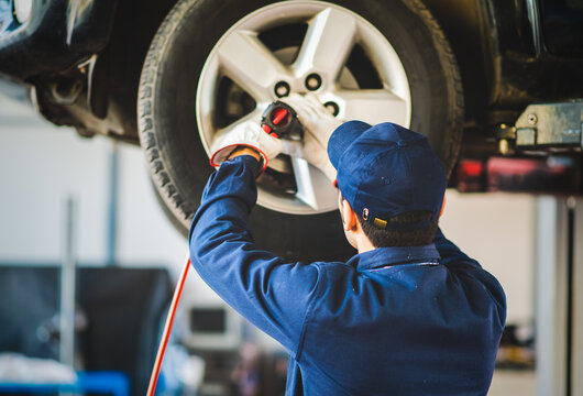 Mechanician changing car wheel in auto repair shop