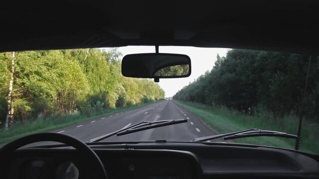 An old retro unic car driving slowly on a bumpy and narrow highway, interior view of the dashboard