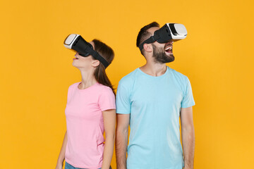 Excited young couple two friends guy girl in blue pink t-shirts posing isolated on yellow wall background studio portrait. People emotions lifestyle concept. Mock up copy space. Watching in headset.