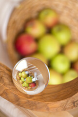 Glass, crystal ball. Wine stand made of olive wood. Wicker basket with green and red apples. Inverted reflection. Interior, comfort at home. Balance. Healthy eating Conceptual.Selective focus