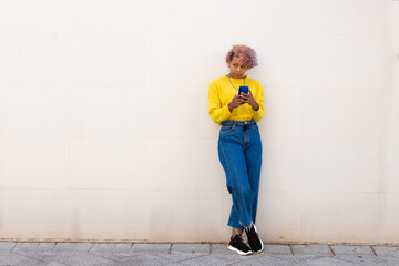 afro american girl with smartphone on the street wall