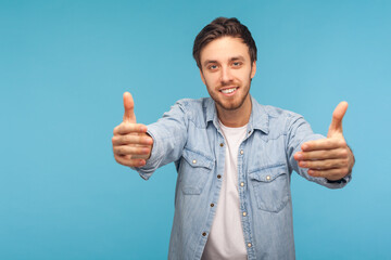 Come into my arms! Portrait of handsome friendly good-natured man in worker denim shirt raising hands to embrace, inviting for free hugs and smiling kind. studio shot isolated on blue background