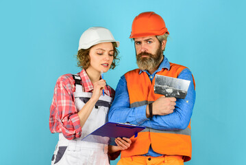 Discussing renovation with contractor. Plastering works. Couple look documents. Woman and man...