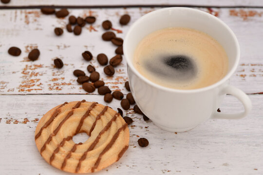 Kaffeepause - Kaffeetasse mit Kaffee und Kaffeebohnen darum verteilt - und dazu gibt es ein Geb&auml;ckst&uuml;ck. 