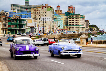 HAVANA, CUBA - NOVEMBER 15, 2017: Old classic vintage cars drive in traffic along famous Malecon avenue in central Havana - the capital of Cuba.