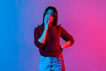 Hmm, need to think. Neon light portrait of thoughtful woman touching chin while contemplating how...