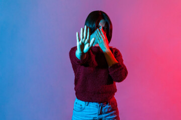 Awful smell! Neon light portrait of displeased woman holding breath, pinching her nose with fingers...