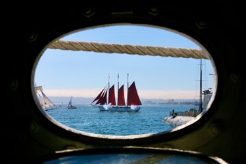 Porthole view of Historic ship at sail, mock battle firing canons, Maritime Museum, Festival of the Sea, San Diego, California, USA