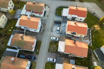 Aerial view of residential houses with red roofs and streets with parked cars in rural town area. Quiet suburbs of a modern european city.