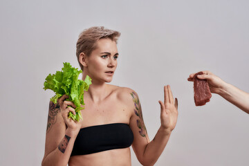 No meat. Attractive tattooed woman with pierced nose refuses to eat meat offered to her, choosing...