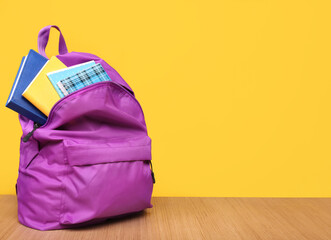 Backpack with stationery on a yellow background. Place for your text.