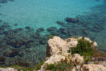 Turquoise surface of waving water in sunshine on tropical rocky beach in Crete, Greece. Copy space.
