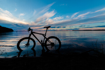 Fototapeta premium evening silhouette of a mountain bike on the lake with a beautiful sunset