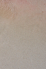 Waving Sea water texture on wet Sandy Beach as a natural background.