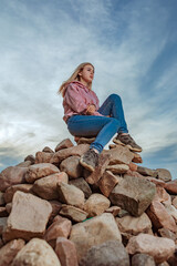 A lonely girl sits on a mountain of rocks