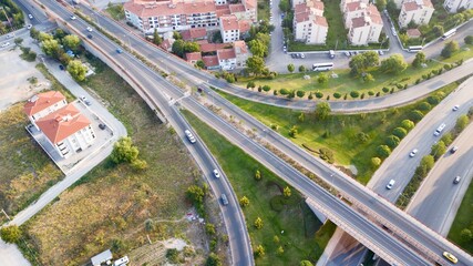 Aerial view of the roundabout on the river. Trees, overpass, buildings and vehicles can be seen. 