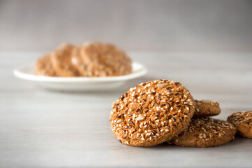 Oatmeal cookies with grains of flax, sunflower and sesame seeds on a wooden background. Selective focus.