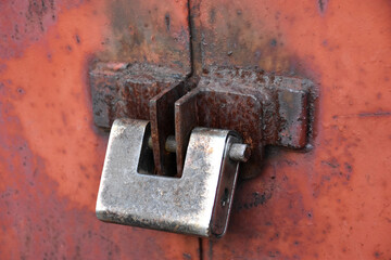 Rusted lock of the garage, fence, door. Metal padlock, red corroded wall