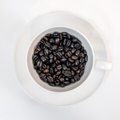 Fresh roasted coffee beans in a white coffee cup on a white background.
