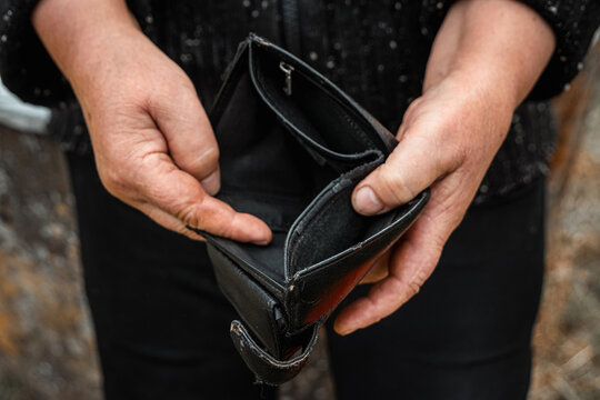 An empty wallet in the hands of a pensioner. Small pension concept, poverty.