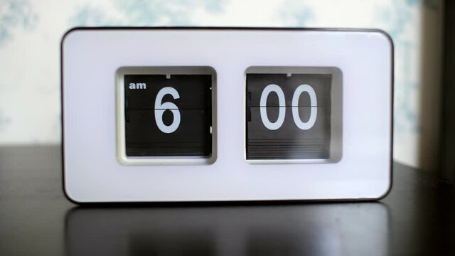 stylish flip clock with white numbers shows 6 am on table