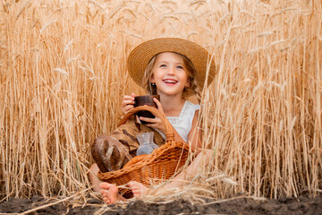 Little blonde girl in wheat field eats bread and drinks milk.eco-friendly farm products © Tina kids photo