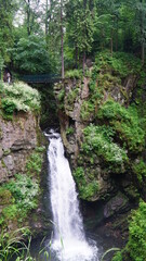 wodospad górski z mostkiem pośród skał
