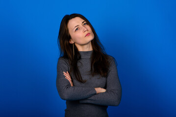 Obraz premium Photo of smiling, cheerful young female in grey dress on blue background