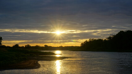 promienisty zachód słońca nad rzeką Odrą pośród chmur - obrazy, fototapety, plakaty