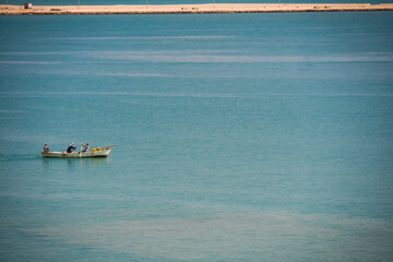 fishermen in the Suez Canal against the background of expensive houses and palm trees