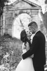 Sunshine portrait of happy bride and groom outdoor in nature location at sunset. Warm summertime. Happy couple with a beautiful bouquet of flowers. Wedding photo. Couple in love. Autumn wedding