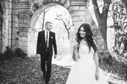 Sunshine portrait of happy bride and groom outdoor in nature location at sunset. Warm summertime. Happy couple with a beautiful bouquet of flowers. Wedding photo. Couple in love. Autumn wedding