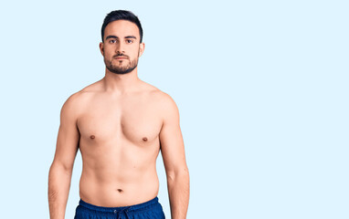 Young handsome man wearing swimwear with serious expression on face. simple and natural looking at the camera.