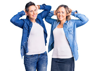 Couple of women wearing casual clothes relaxing and stretching, arms and hands behind head and neck smiling happy