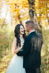 Naklejka premium Groom hugging his laughing bride in green park. Wedding.