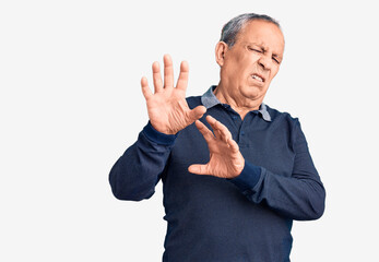 Senior handsome man wearing casual polo disgusted expression, displeased and fearful doing disgust face because aversion reaction. with hands raised