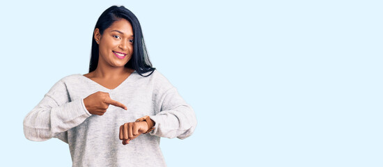 Hispanic woman with long hair wearing casual clothes in hurry pointing to watch time, impatience,...
