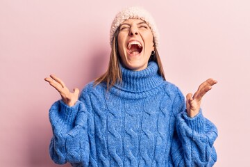 Young beautiful woman wearing winter clothes celebrating mad and crazy for success with arms raised and closed eyes screaming excited. winner concept