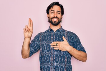 Young handsome hispanic bohemian man wearing hippie style over pink background smiling swearing...