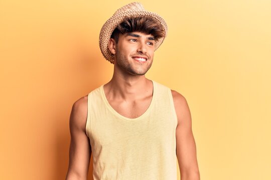 Young hispanic man wearing summer hat looking to side, relax profile pose with natural face and confident smile.