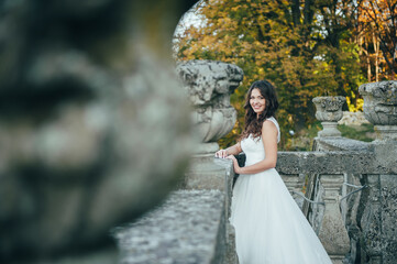 Happy beautiful young bride outside on a summer meadow at the sunset