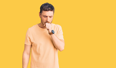 Handsome young man with bear wearing casual yellow tshirt feeling unwell and coughing as symptom for cold or bronchitis. health care concept.